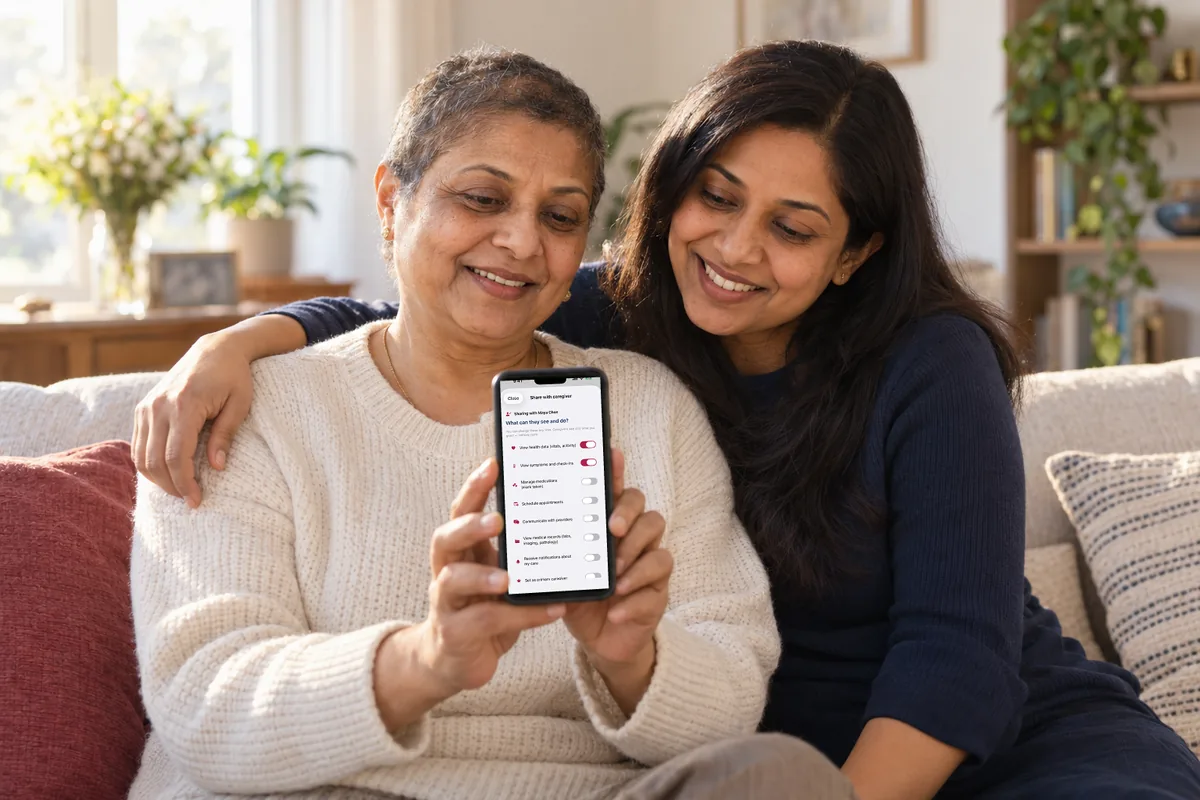 A woman with short regrowth hair shows her phone to her adult daughter, who has an arm around her; the screen shows caregiver sharing in MyBC Health.
